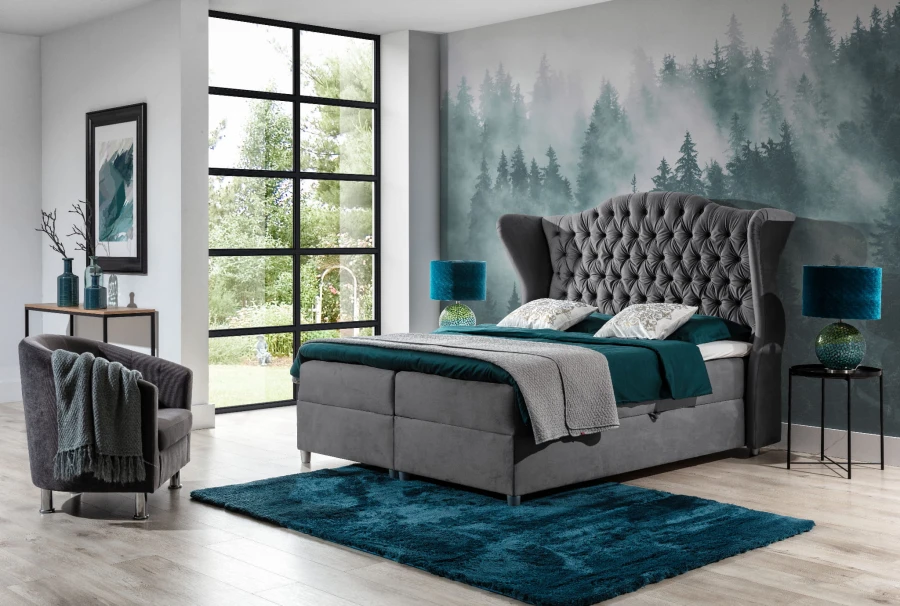 Graues Boxspringbett mit gestepptem Kopfteil in modernem Schlafzimmer mit Wald-Motivtapete.
