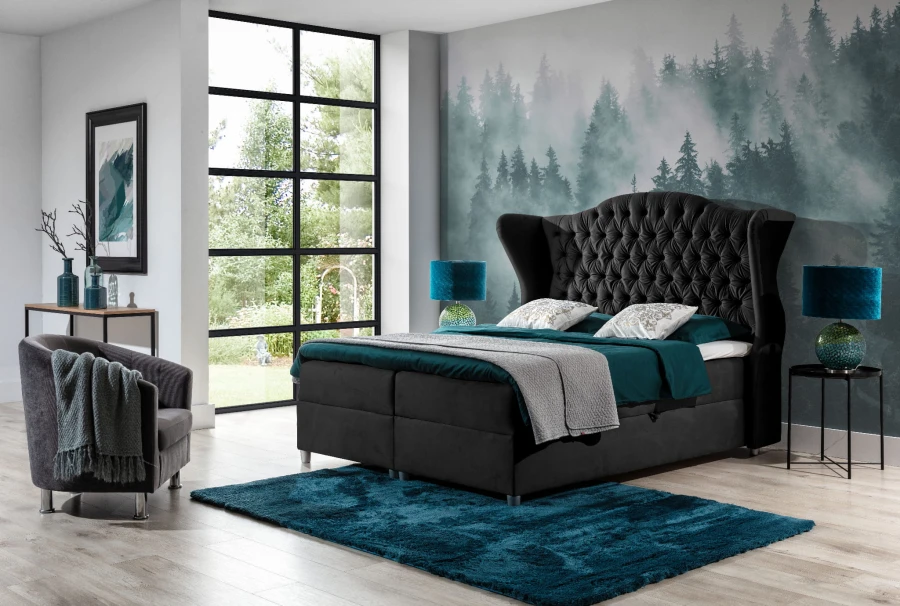 Schwarzes Boxspringbett mit hohem, gestepptem Kopfteil und dekorativer Waldtapete im Schlafzimmer.