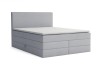 Hellgraues Boxspringbett mit schlichtem Kopfteil und Topper vor weißem Hintergrund freigestellt.
