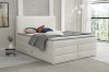 Modernes weißes Boxspringbett mit hohem Kopfteil im hellen Schlafzimmer