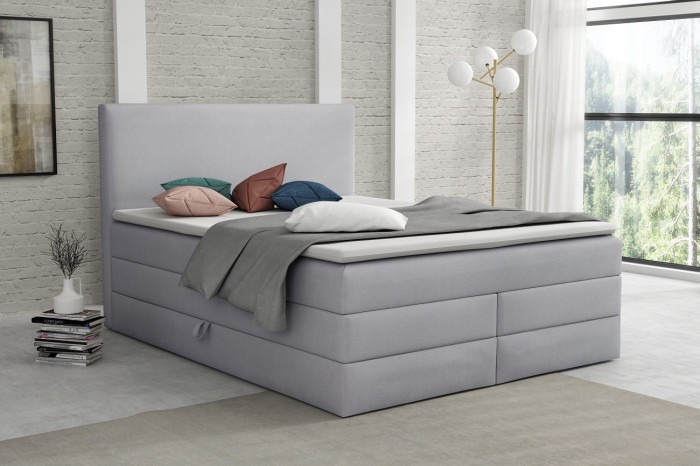 Komfortables hellgraues Boxspringbett im zeitlosen Design für gemütliche Nächte.