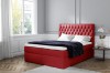 Rotes Boxspringbett mit eleganter Knopfheftung am Kopfteil in einem hellen Zimmer
