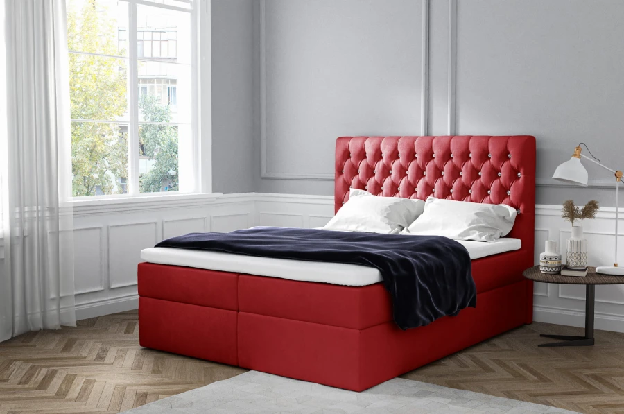 Rotes Boxspringbett mit eleganter Knopfheftung am Kopfteil in einem hellen Zimmer