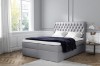 Hellgraues Boxspringbett mit gepolstertem Kopfteil in modernem Schlafzimmer.