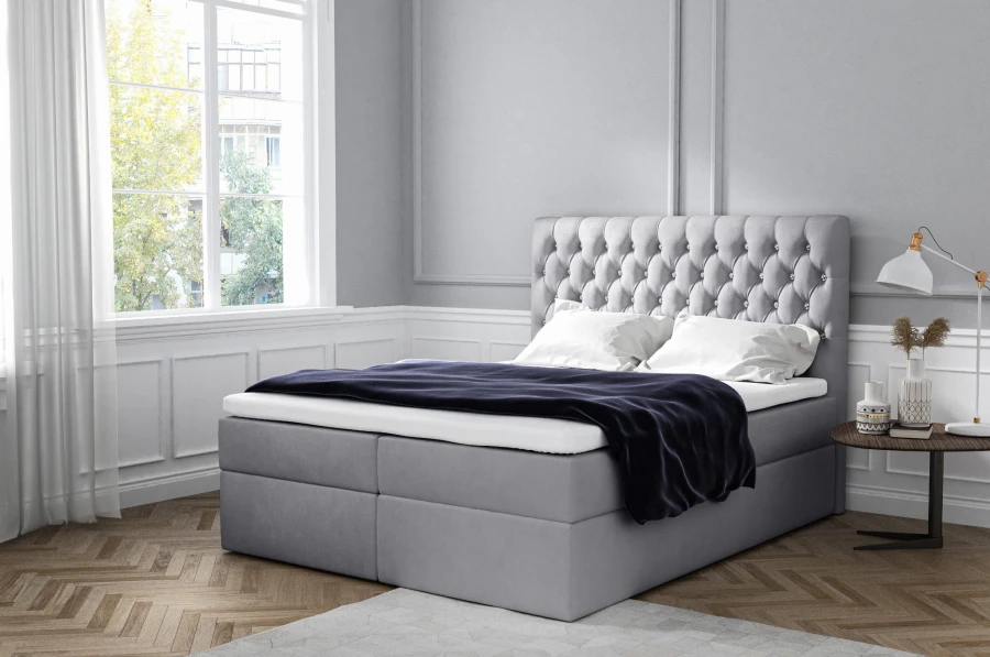 Hellgraues Boxspringbett mit gepolstertem Kopfteil in modernem Schlafzimmer.