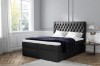 Schwarzes Boxspringbett mit gestepptem Chesterfield-Kopfteil und dunkler Decke.