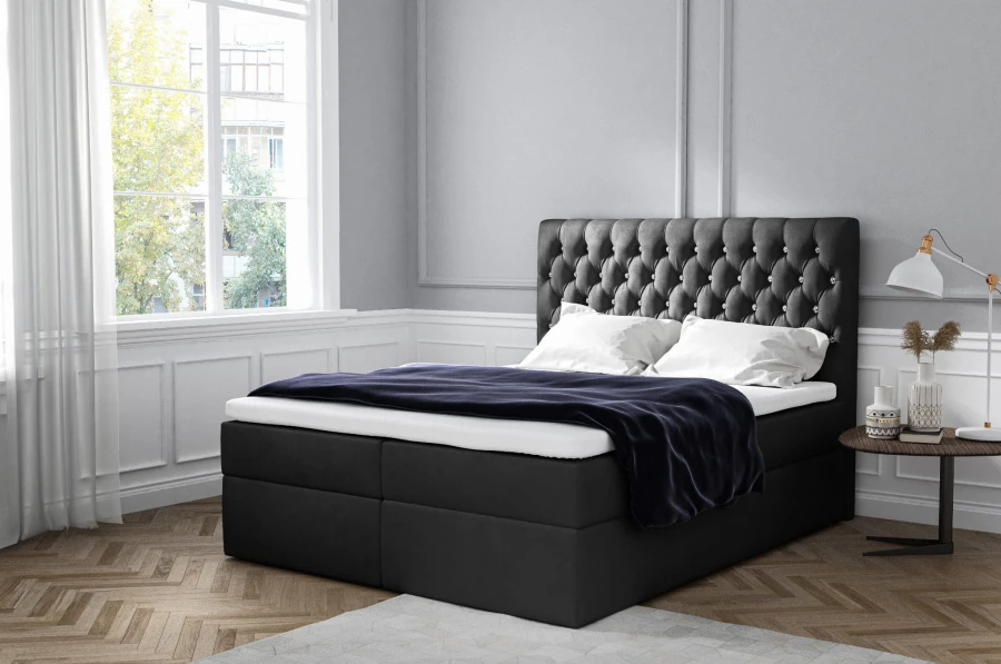 Schwarzes Boxspringbett mit gestepptem Chesterfield-Kopfteil und dunkler Decke.