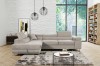 Beiges Ecksofa in modernem Wohnzimmer mit Ziegelwand und Regal.