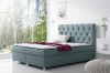 Hellblaues Boxspringbett mit gestepptem Kopfteil und glänzenden Ziersteinen.