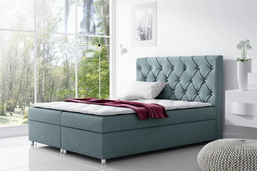 Hellblaues Boxspringbett mit gestepptem Kopfteil und glänzenden Ziersteinen.