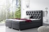 Elegantes Boxspringbett in Anthrazit mit kristallbesetztem Kopfteil vor einem großen Fenster.