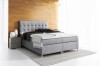 Graues Boxspringbett mit komfortabler Matratze und stilvollen Holzfüßen.
