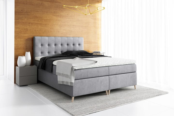 Graues Boxspringbett mit komfortabler Matratze und stilvollen Holzfüßen.