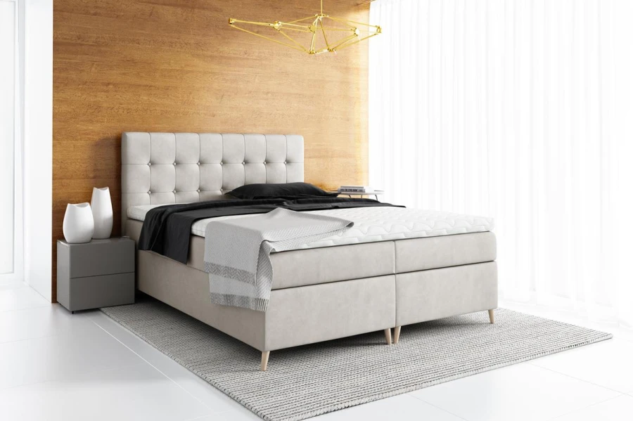 Modernes Boxspringbett in Beige mit gestepptem Kopfteil in einem hellen Schlafzimmer.