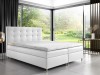 Weißes Boxspringbett mit gestepptem Kopfteil in modernem Schlafzimmer mit Gartenblick.