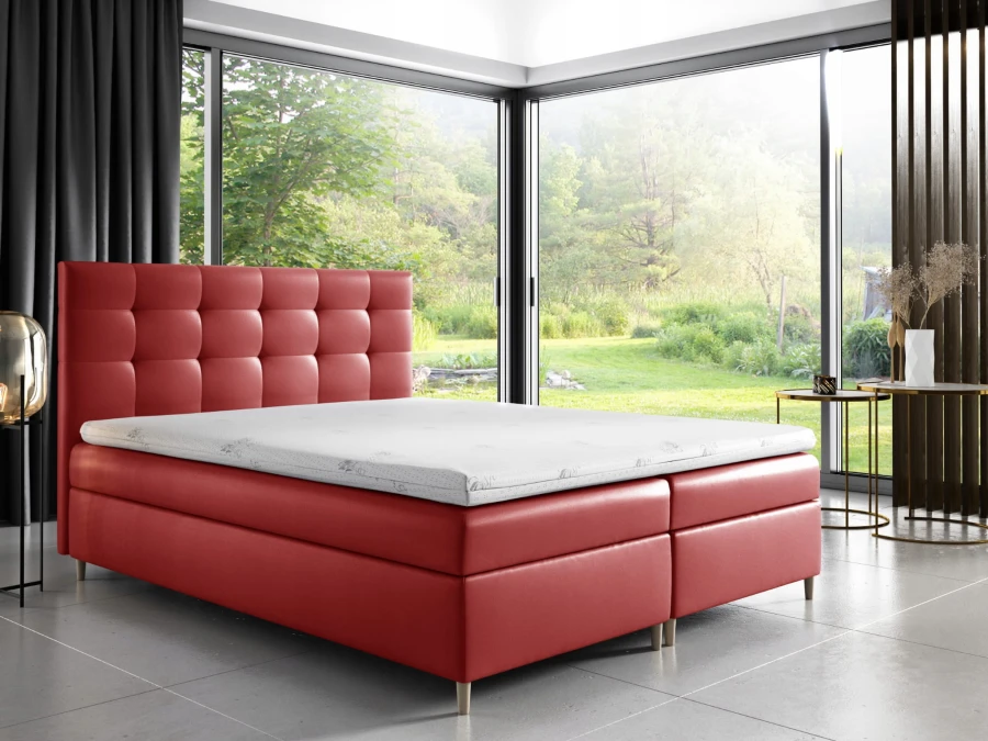 Rotes Boxspringbett als moderner Farbakzent im Schlafzimmer mit Blick in die Natur.