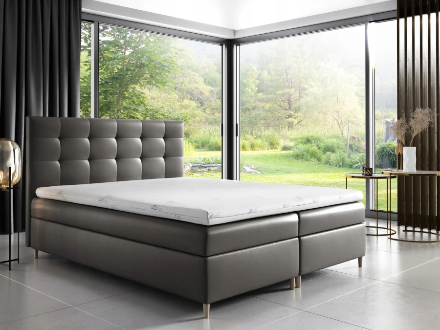 Graues Boxspringbett mit gestepptem Kopfteil in modernem Schlafzimmer mit Panoramablick.