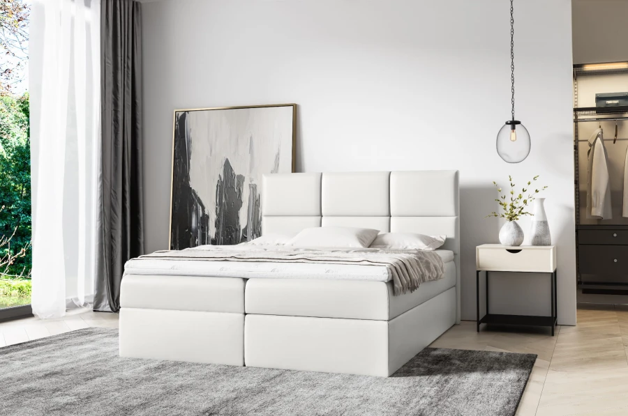 Weißes Boxspringbett im modern eingerichteten Schlafzimmer mit Teppich