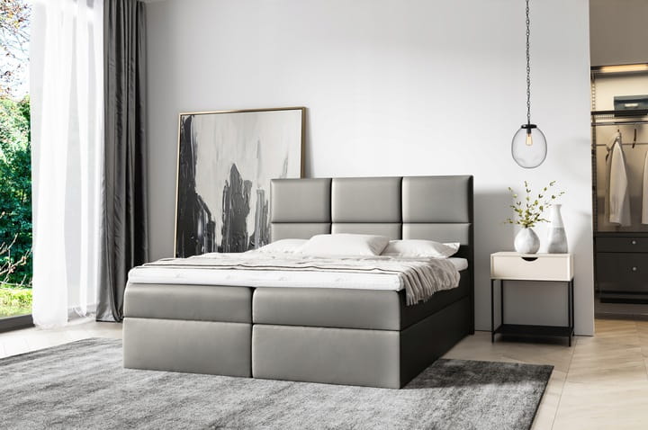 Graues Boxspringbett mit stilvoller Steppung in modern eingerichtetem Schlafzimmer.