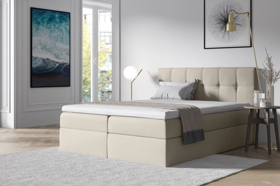 Beiges Boxspringbett mit modernem gestepptem Kopfteil und weißem Topper.