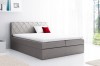 Hellgraues Boxspringbett mit gestepptem Kopfteil und weißem Topper in modernem Schlafzimmer.