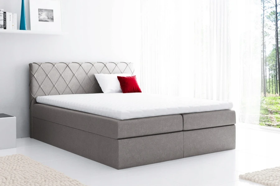 Hellgraues Boxspringbett mit gestepptem Kopfteil und weißem Topper in modernem Schlafzimmer.