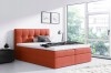Modernes Boxspringbett in Orange mit gepolstertem Kopfteil im hellen Schlafzimmer.