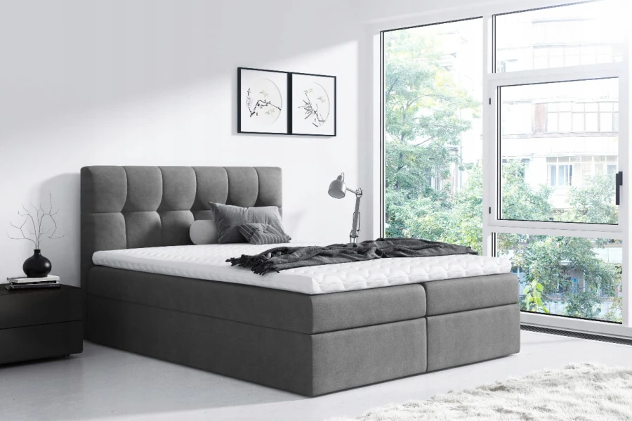 Modernes graues Boxspringbett mit gestepptem Kopfteil im hellen Schlafzimmer.