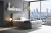 Modernes graues Boxspringbett im Schlafzimmer mit Skyline-Blick durch große Fensterfront.