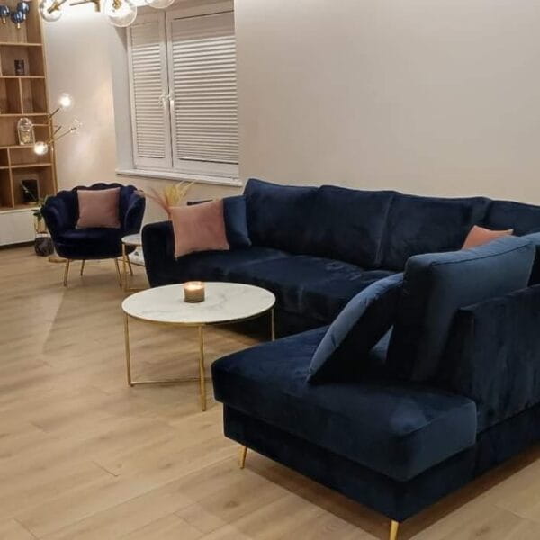 Dunkelblaues Ecksofa aus Samt in modernem Wohnzimmer mit Couchtisch und Sessel.
