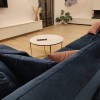 Modernes Wohnzimmer mit blauem Samtsofa, rosa Kissen und rundem Marmortisch.