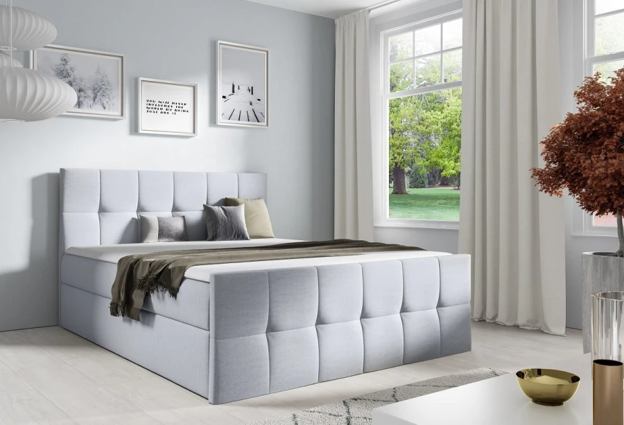 Modernes hellgraues Boxspringbett mit gestepptem Kopfteil im Schlafzimmer.