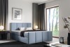 Modernes blaues Polsterbett im hellen Schlafzimmer mit Waldblick.
