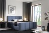 Stilvolles blaues Boxspringbett mit gepolstertem Kopfteil.