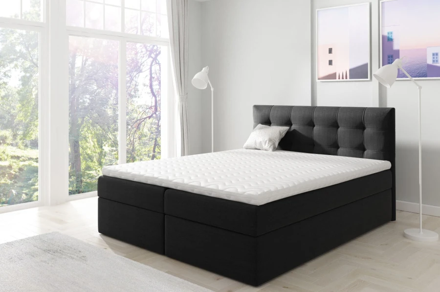 Modernes schwarzes Boxspringbett mit gepolstertem Kopfteil vor einer hellen Fensterfront