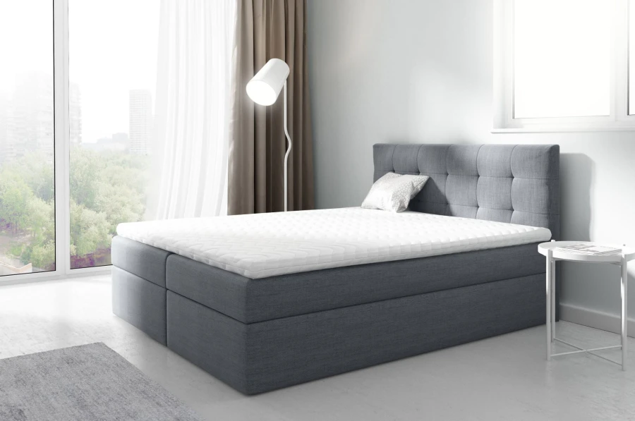 Graues Boxspringbett mit gestepptem Kopfteil in einem modernen Schlafzimmer mit City-View