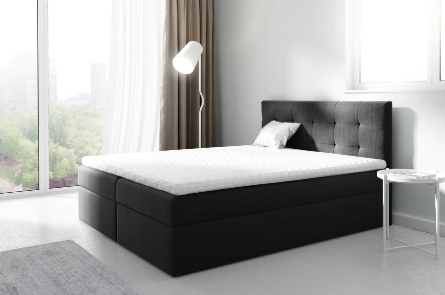 Anthrazitfarbenes Boxspringbett mit weißem Topper und stilvollem Kopfteil.