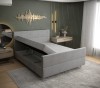 Graues Boxspringbett mit aufgeklapptem Bettkasten für extra Stauraum.