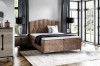 Braunes Boxspringbett mit strukturiertem Stoffbezug im gemütlichen Schlafzimmer.