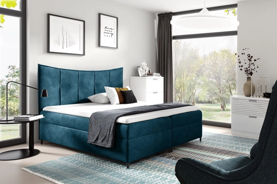 Blaues Boxspringbett in modernem Schlafzimmer mit großem Fenster und hellem Teppich.