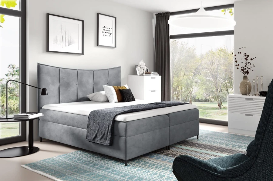 Graues Boxspringbett in hellem, modernem Schlafzimmer-Ambiente mit Dekoration.