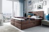 Braunes Boxspringbett in gemütlich eingerichtetem Schlafzimmer mit Stadtblick