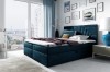 Modernes Boxspringbett in Blau mit gestepptem Kopfteil und Stadtblick.