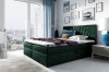 Dunkelgrünes Boxspringbett mit elegantem Kopfteil in modernem Schlafzimmer.
