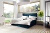 Dunkelblaues Boxspringbett mit Rautenmuster-Kopfteil und Waldblick