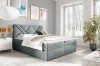 Elegantes graues Boxspringbett mit gestepptem Kopfteil in modernem, hellem Schlafzimmer-Ambiente.