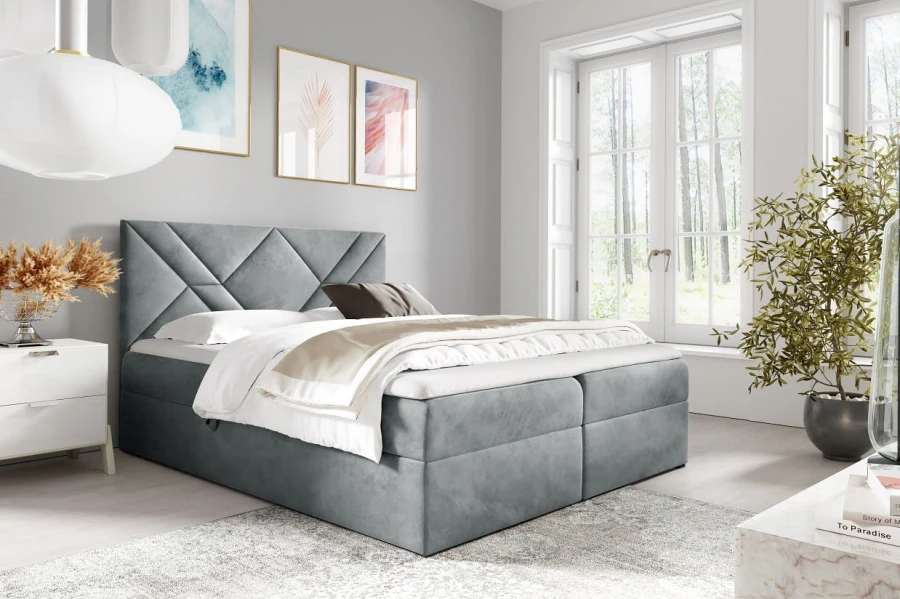Elegantes graues Boxspringbett mit gestepptem Kopfteil in modernem, hellem Schlafzimmer-Ambiente.