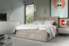 Beiges Boxspringbett mit gestepptem Kopfteil in einem hellen, modernen Schlafzimmer.