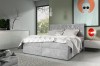 Hellgraues Boxspringbett mit dekorativer Steppung im Schlafzimmer-Ambiente.