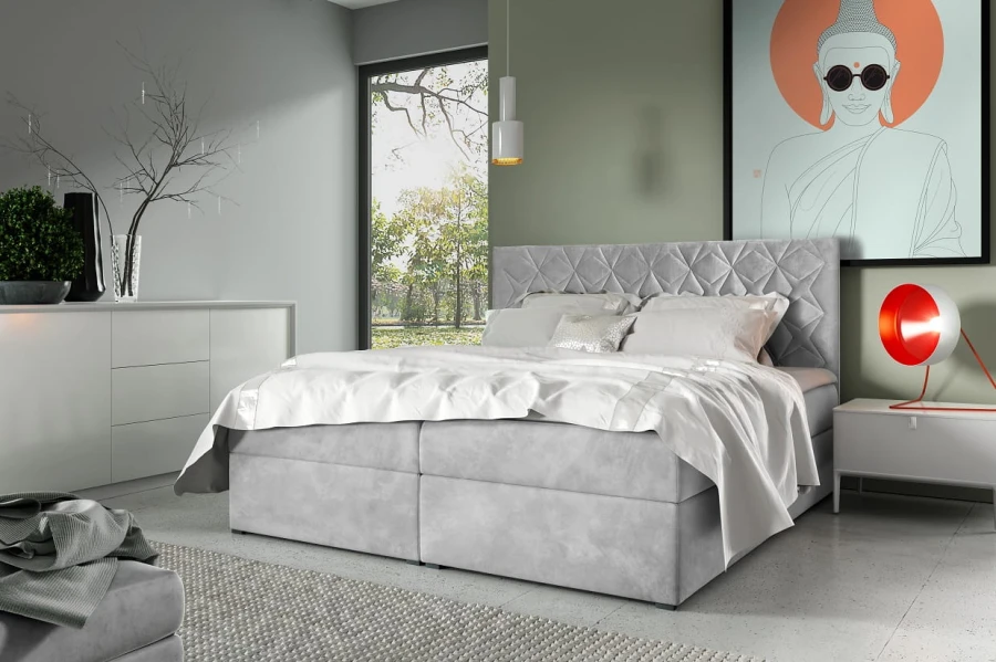 Hellgraues Boxspringbett mit dekorativer Steppung im Schlafzimmer-Ambiente.